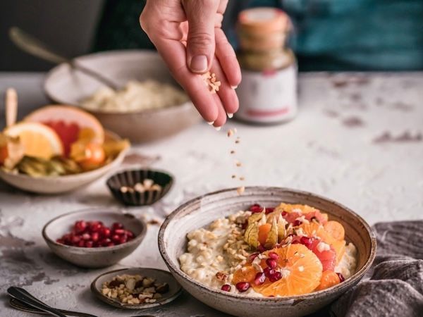 Frühstücksschale mit Obst wird mit einer Kraut-und-Korn-Gewürzmischung bestreut